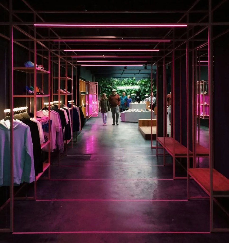 Amir X Millennium clothing boutique interior with apparel racks under pink neon lighting